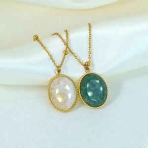 Detailed macro view of oval faceted gemstones in opal white and emerald green with gold chain