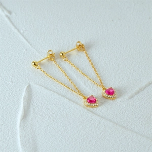 Detail of gold heart earrings with pink stones and white diamonds on white marble