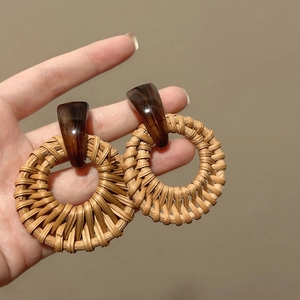 Detailed macro view of woven rattan texture and resin stud on bohemian drop earrings