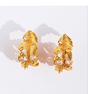 Detailed view of golden feather earrings with shimmering cubic zirconia inlay on white background