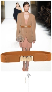 Detail of a brown elastic waist belt with a cylindrical gold buckle for dresses