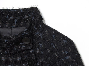 Close-up of metallic tweed fabric with silver threads and black resin buttons on jacket