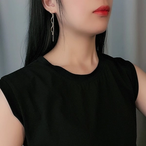 Detailed side view of long wave gold earrings worn by model showing elegant tassel length