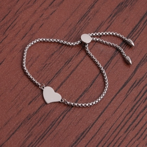 Polished silver heart bracelet with adjustable box chain on a wooden background