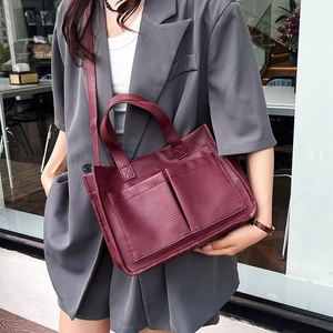 Model wearing a burgundy large leather tote bag with gray suit in street style