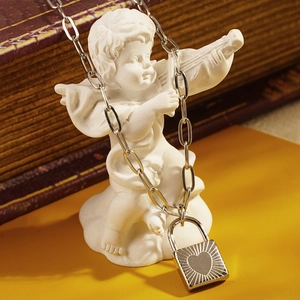 Minimalist silver heart lock pendant necklace displayed on a white angel sculpture decor