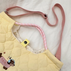 Detail of cartoon dog embroidery and quilted texture on a large capacity yellow handbag