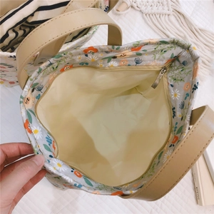 Detailed view of floral tote bag showing beige leather handles and gold zipper closure