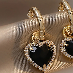 Elegant gold heart earrings with black stone and rhinestones on soft gold fabric
