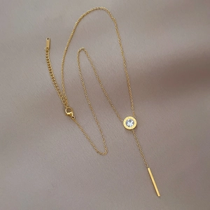 Close-up of golden Roman numeral circle pendant with diamond and long tassel chain