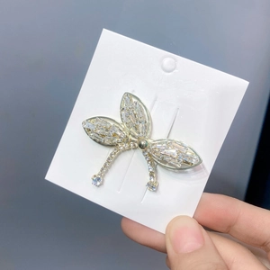 Detail of a golden dragonfly hair clip with clear zircons on a white card display