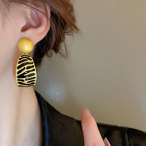 Close-up of model wearing vintage black and gold zebra pattern striped enamel earrings
