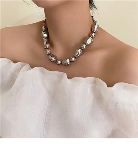 Detail of silver irregular metallic beads necklace worn on neck in modern French style
