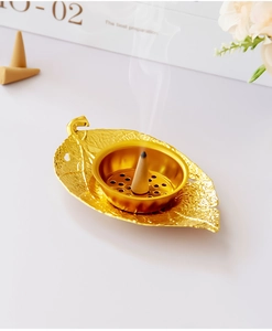 Macro detail of leaf-shaped gold metal incense burner with smoke and intricate vein textures