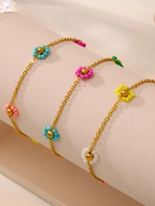 Detail of handmade colorful bead flower bracelet on a beige cylindrical display stand