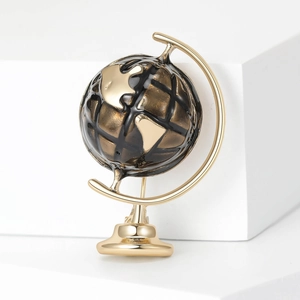 Detail of a vintage globe brooch with gold frame and enamel map on white background