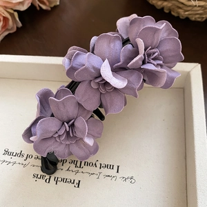 Vue détaillée de la pince à cheveux fleur en tissu violet sur un plateau chic