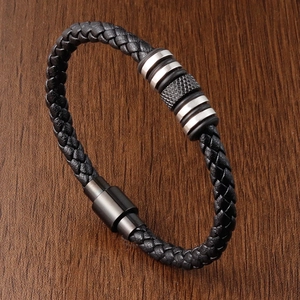 Close-up of black braided leather bracelet with magnetic clasp on wood background