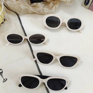 Retro cream white cat-eye sunglasses set with dark grey lenses in a lifestyle arrangement