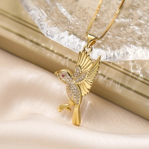 18K gold plated necklace with zircon bird pendant on elegant beige silk background