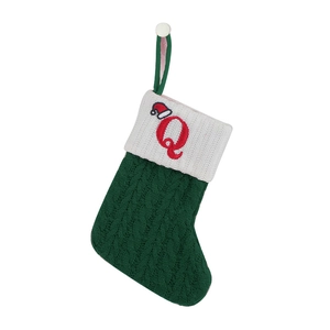 Detailed knit texture of green Christmas stocking featuring red embroidered letter Q