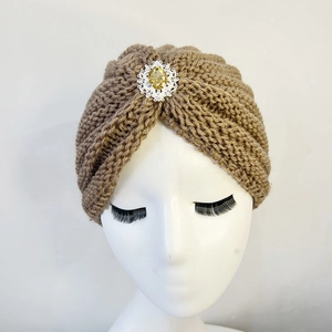 Close-up of camel knit turban hat featuring a central yellow gemstone and silver trim