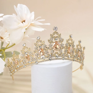 Detail of a luxury gold tiara with amber gemstones and crystals on a white pedestal