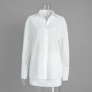 Detail of white pleated long-sleeve shirt showing textured fabric and lapel design
