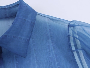 Detailed close-up of blue gradient organza shirt fabric with vertical textures and collar