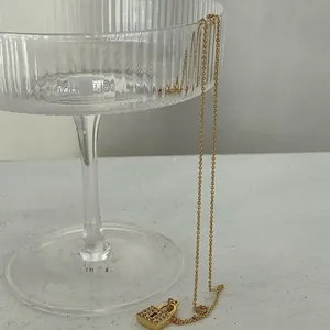 Detail of 18k gold plated lock pendant with red gemstone on textured glass tray
