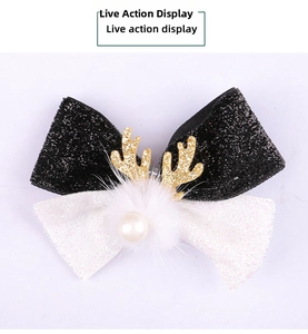 Detail of Christmas bow hair clip with gold glitter antlers and white pom-pom embellishment