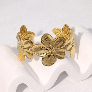 Elegant gold flower cuff bracelet with brushed metal texture on a white minimalist base