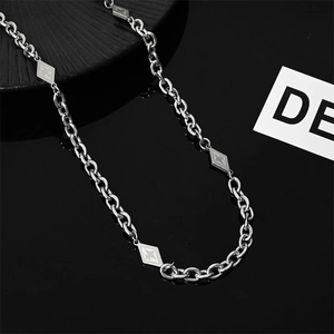 Macro view of titanium steel chain necklace with diamond-shaped charms on black reflective base