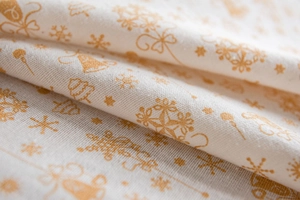Close-up of white festive tablecloth featuring golden Christmas tree and snowflake patterns