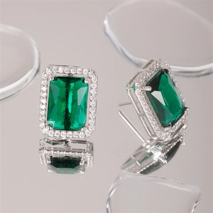 Detail of emerald cut green zircon earrings with halo pavé setting on reflective base
