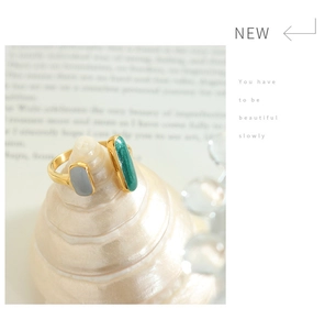 Adjustable gold plated titanium ring with blue and emerald enamel on a white seashell