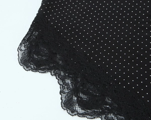 Close-up of black polka dot fabric with delicate black lace trim detailing