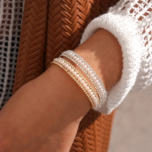 Close-up of luxury multilayer bracelets with pearls and sparkling zircons on wrist