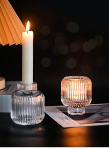 Close-up of ribbed glass candle holders with warm candlelight and soft bokeh background