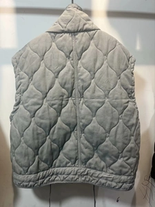 Close-up of grey quilted vest with diamond pattern and stand-up collar detail