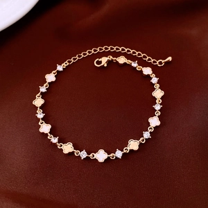 Dettaglio di un bracciale a quadrifoglio dorato con madreperla bianca e zirconi