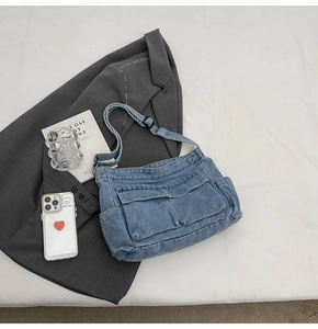 Detail of blue denim crossbody bag with multiple utility pockets and adjustable strap