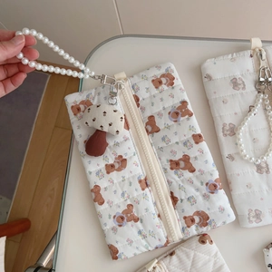 Detail of quilted bear cotton pouch with pearl strap and mushroom charm accessory