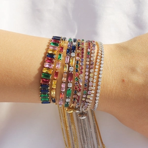 Stacked colorful zircon bracelets featuring rectangular and round cut crystals on a wrist