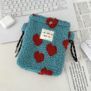 Détail du sac en peluche cyan avec motif de cœur rouge et boucle de cordon en métal