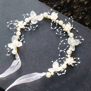 Detailansicht eines handgemachten Blumenstirnbands mit weißen Blüten und Perlen