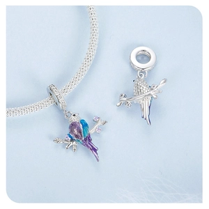 Détail macro du charme oiseau avec pierre violette poire et émail bleu sur bracelet argent