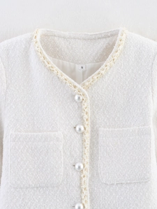 Vue détaillée du tissu en tweed blanc avec bouton perle et bordure tressée dorée