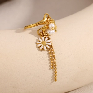 Detail view of 18K gold plated tassel ring with white enamel daisy and pearl pendants