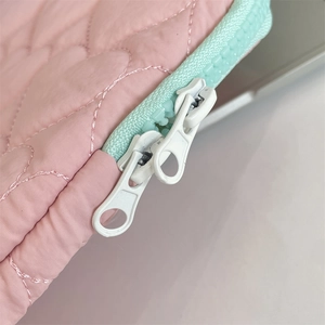 Close-up of heart-shaped quilted fabric and dual zippers on a laptop sleeve